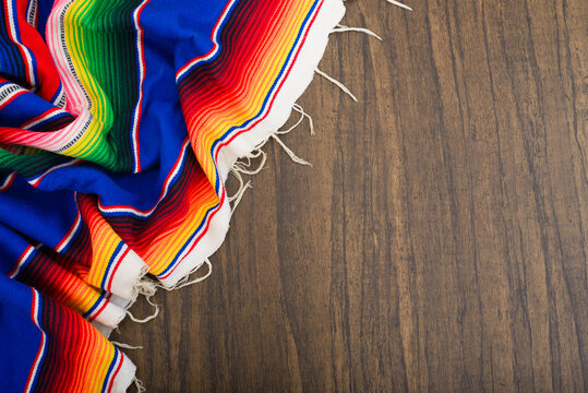 Colorful serape on wooden table. Typical colorful fabric from Mexico. Texture, background.