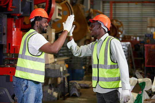 African factory workers or engineer giving high five in the factory