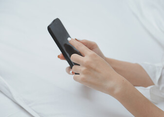 Happy young female in casual clothes smiling and looking at camera while using laptop on bed in bedroom at home