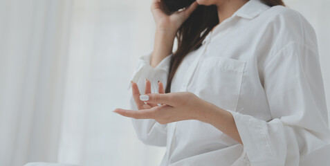 Happy young female in casual clothes smiling and looking at camera while using laptop on bed in bedroom at home
