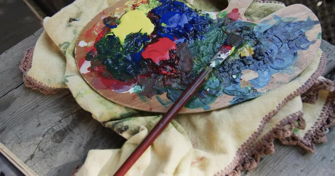 Close up of paints and brush on table in sunny garden, slow motion