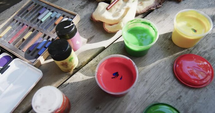 Close up of paints and brushes on table in sunny garden, slow motion