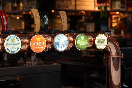 Tel-Aviv, Israel - July 6, 2023:Bar pumps for dispensing draught beer from the metal storage kegs in a pub or bar. Cranes for bottling beer in a bar