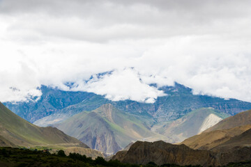 Dark Dramatic Desert Landscape with Foggy Mountains and Distant Houses in Muktinath, Mustang, Nepal