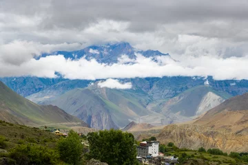 Photo sur Plexiglas Dhaulagiri Dark Dramatic Desert Landscape with Foggy Mountains and Distant Houses in Muktinath, Mustang, Nepal