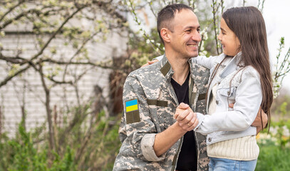 Soldier in Ukrainian military uniform hugging his daughter. Family reunion