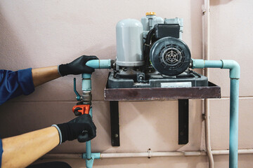 Technician plumber using a wrench to repair a water pump pipe. Concept of maintenance, fix water...
