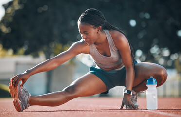 Exercise, sports and a woman stretching outdoor on a track for running, training or workout. African athlete person at stadium for legs stretch, fitness and muscle warm up or body wellness on ground