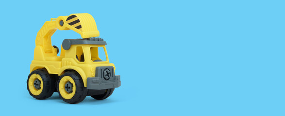 Yellow plastic truck toy isolated on blue background. construction vechicle truck. a copy space for banner of toy store.