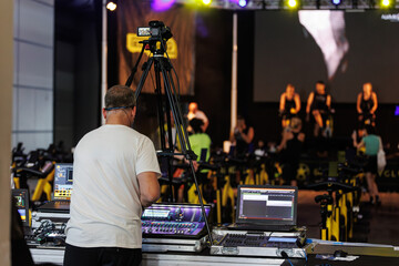 Fototapeta na wymiar Lighting and Sound Technician and Broadcast Operator at Work in the BackStage during a Public Event