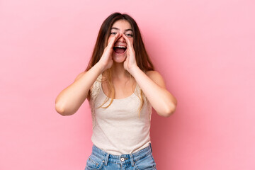 Young caucasian woman isolated on pink background shouting and announcing something