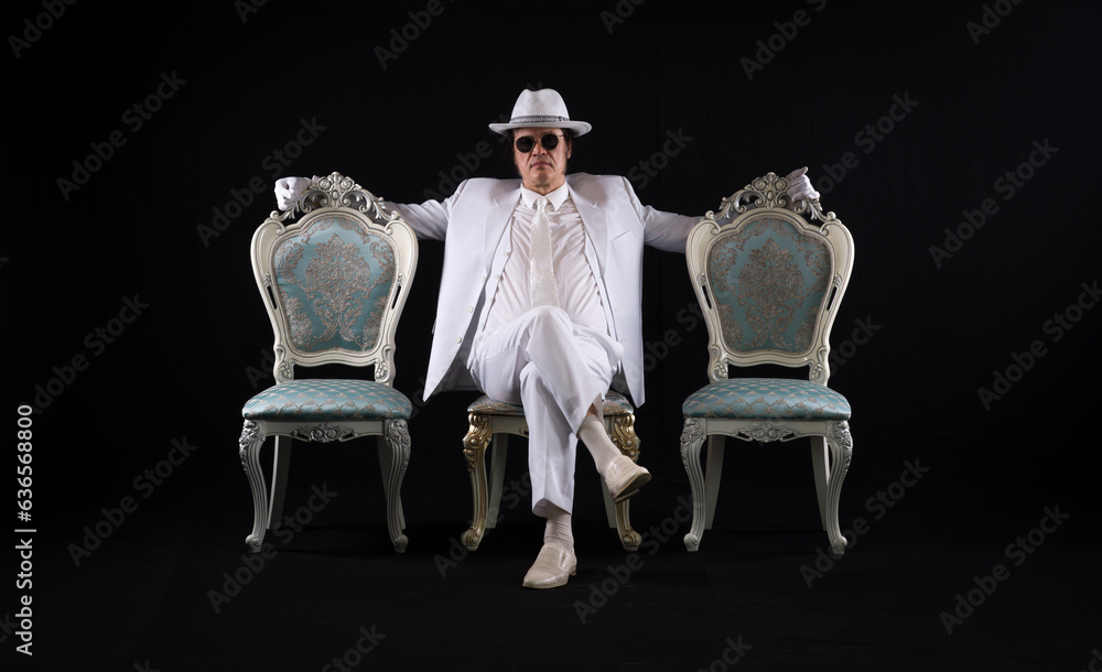 Canvas Prints rich gentleman in a white suit sits on a chair, black studio background