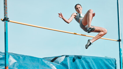 High jump, woman and fitness with exercise, sport and athlete in a competition outdoor. Jumping, workout and training for performance with action, energy and contest with female person and athletics - obrazy, fototapety, plakaty