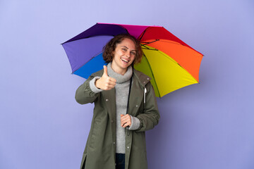 English woman holding an umbrella isolated on purple background with thumbs up because something good has happened