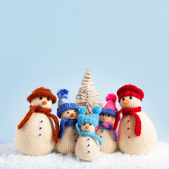Knitted snowmen in colorful hats and scarves on a blue background. Concept of Christmas, New Year and winter fairy tale. Creative knitting of toys for children, home decoration.
