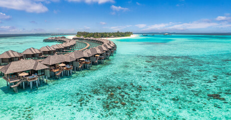 Aerial view of Maldives island, luxury water villas wooden pier path resort. Beautiful sky and...