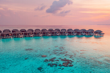 Aerial sunset on Maldives island, luxury water villas resort. Beautiful sky clouds beach nature background. Summer vacation, exotic panoramic travel. Colorful seascape reef coast, inspire landscape 