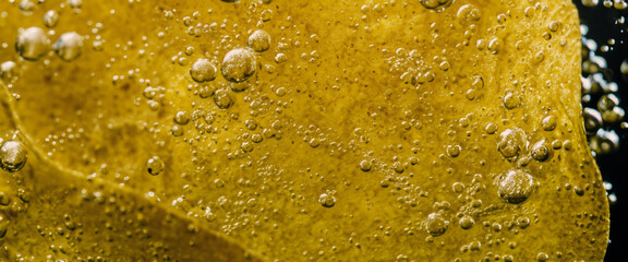 Deep fried potato chips under golden oil water. Frying rounded potatoes chip with hot boiling oil bubbles. Fast food and snack. Underwater cooking oily french fries or potatos chips in oils background