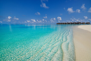Aerial view of Maldives island, luxury water villas wooden pier path resort. Beautiful sky and ocean bay beach background. Summer vacation travel destination. Paradise aerial landscape panoramic coast