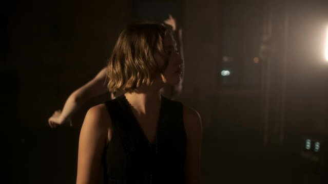A young beautiful girl walks between the dancing people and watches them. The concept of modern dance. Graceful movements. Beautiful body movements.