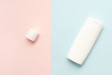 Flat lay of cosmetic bottles and tubes on two colored background