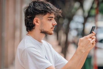 portrait of young man in the street looking at the mobile phone