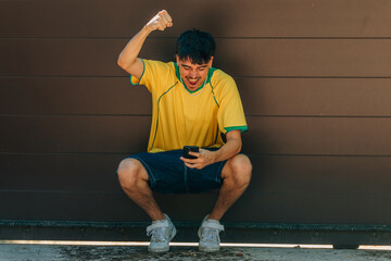 Fototapeta premium young man with mobile phone or smartphone and yellow t-shirt looking at mobile phone