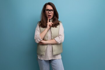 positive young brunette businesswoman with black rimmed glasses on studio background with copy space