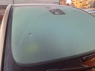 Icy car from winter temperatures. Frost coats car, windshield view.