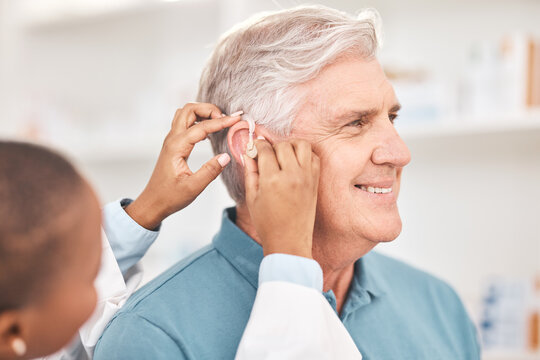 Helping, man and doctor with hearing aid, technology or healthcare or medical device consultation for deaf patient with tinnitus. Listening, test and exam ear tech with nurse or senior male in clinic