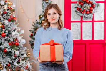 Obraz na płótnie Canvas Portrait of a young woman with a gift in her hands on the background of a Christmas tree.