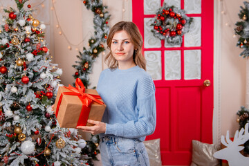 Obraz na płótnie Canvas Portrait of a young woman with a gift in her hands on the background of a Christmas tree.