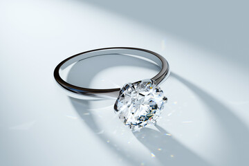 Diamond ring laying in a spotlight on white background. Solitaire engagement ring with a round brilliant cut stone.