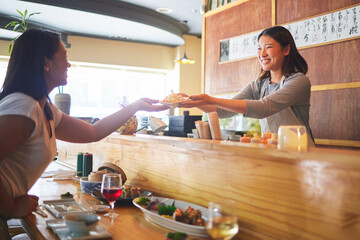 Sushi, happiness and restaurant people, customer and Asian waitress giving food plate, order or product. Japanese cashier, server or startup small business owner with meal for happy client