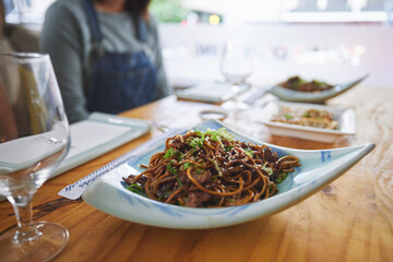 Plate, eating and noodles at a restaurant on a table for Chinese food at lunch. Closeup, health and Asian cuisine for dinner, hungry or a meal at a fine dining cafe for a traditional snack or supper