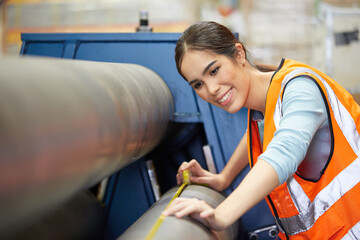 female factory worker using tape measure and measuring the length of the steel pipe in the factory