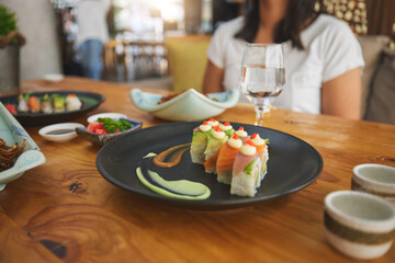 Table, eating and people with sushi at a restaurant for fish, Chinese food or hungry. Closeup, plate and a person with seafood, lunch or dinner at a fine dining cafe for Asian cuisine or health