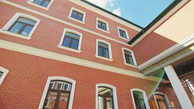 Exterior of red brick building with dark windows. Construction of public facility on construction site. Construction process of building