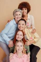 Group of smiling multiethnic women wearing breast cancer pink ribbon hugging, support each other...
