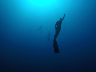 Freediver coming up from a deep dive along the line with divers in background. Gili Air, Indonesia