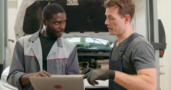 two international mechanics using modern technolodies when repair broken cars Slow motion Guys use professional OBD software, Vehicle diagnostics tool, men check engine pressure, tire pressure online