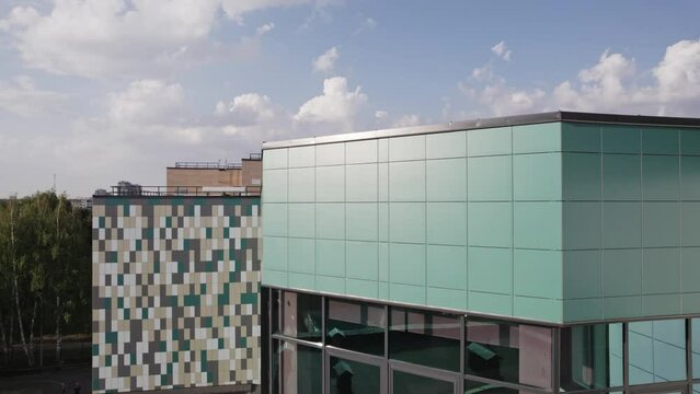 Colorful school building in residential area. Exterior of new educational complex of blue color facade with students closeup aerial view