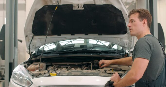 Caucasioan mechanic greeting African American owner of car. they are talking discussing the process of reparing vehicle slow motion, back rare view Slow motion