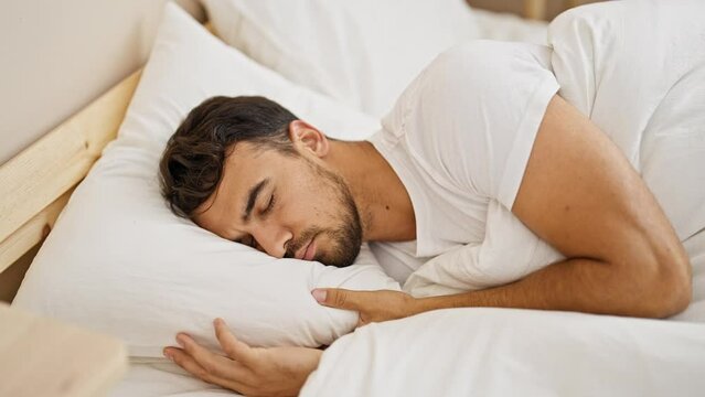 Young hispanic man lying on bed asleep at bedroom