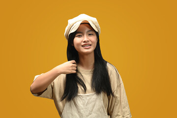 Portrait of Asian teenage girl wearing casual clothes posing isolated on yellow background.