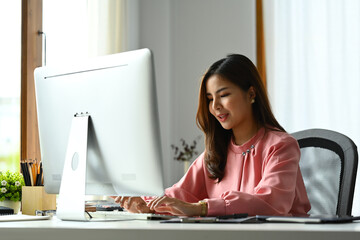 Image of gorgeous businesswoman typing on keyboard, doing online data market analysis at office