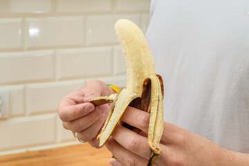 Mężczyzna obiera banana ze skórki © Paweł Kacperek