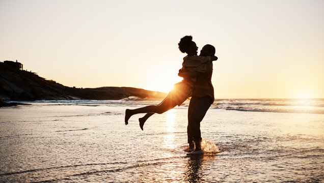 Beach sunset, silhouette and couple hug, celebrate and enjoy romantic time together, bonding and relax in sea water. Wellness, summer freedom and dark shadow of people embrace on tropical anniversary
