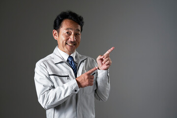 右側を指差すミドルエイジの作業員　黒背景