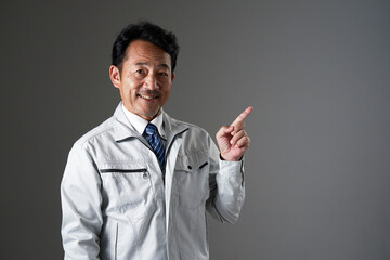 右側を指差すミドルエイジの作業員　黒背景